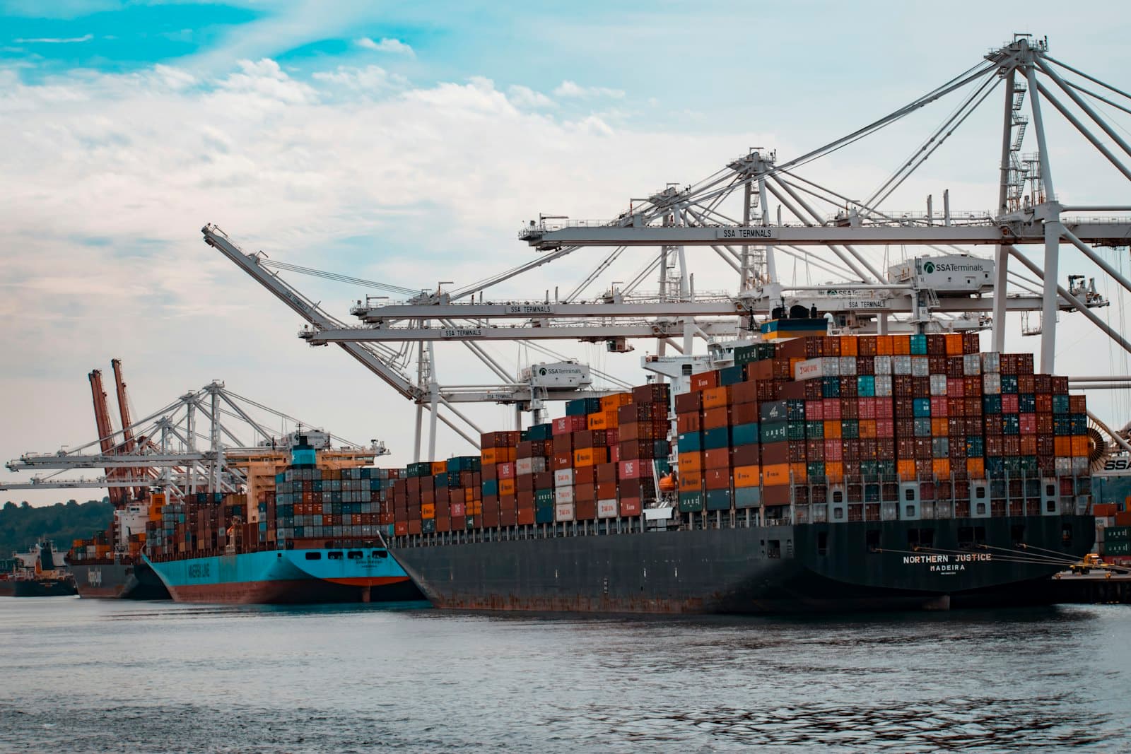 Container cranes and stacked shipping containers at a port terminal.
